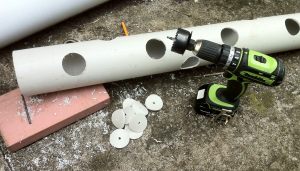drilling holes for strawberries in PVC tube 